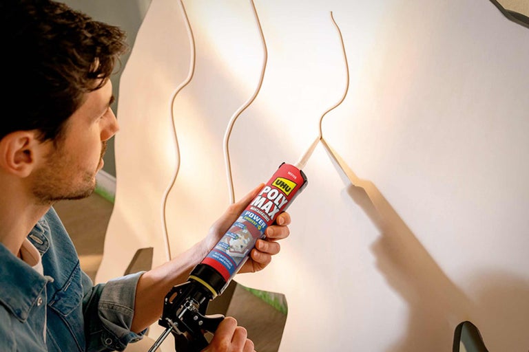 Mann verwendet Montagekleber UHU Poly Max auf einer Wandverkleidung.