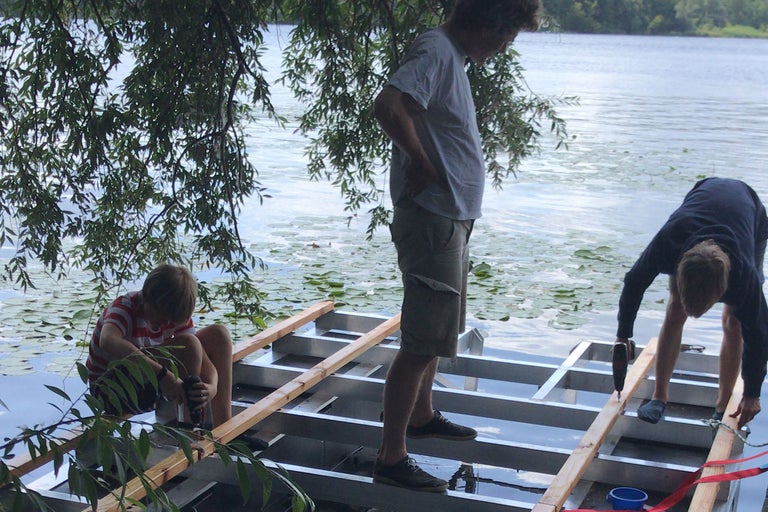 Personen bauen ein Floß auf einem See mit Seerosen