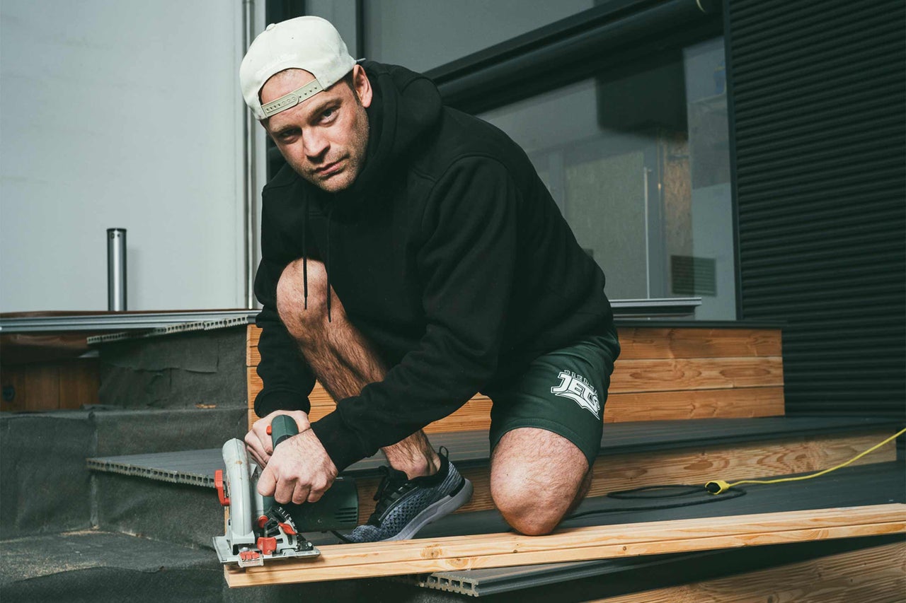 Mann kniet und schneidet Holz mit einer Handkreissäge für ein Bauprojekt