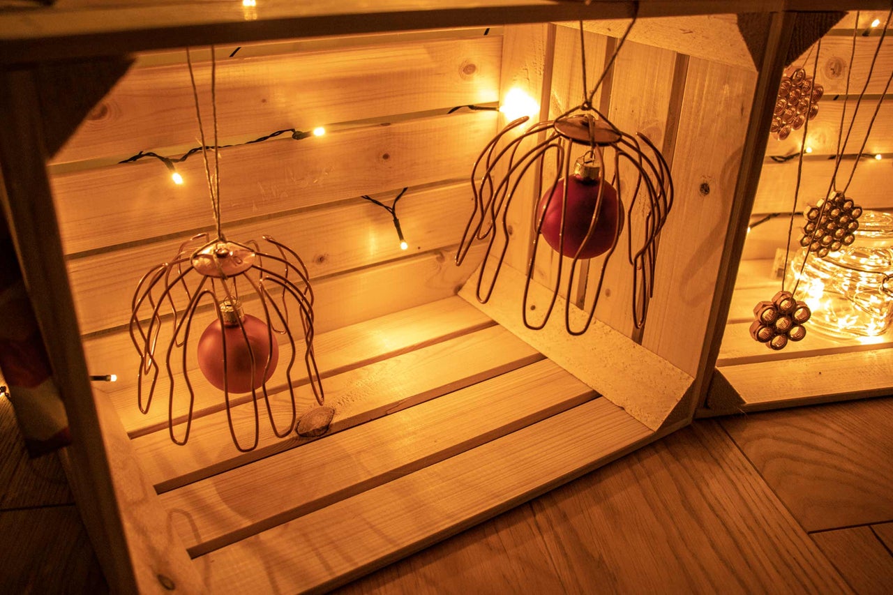 Dekorative Holzkiste mit Christbaumkugeln und Lichterkette für eine festliche Atmosphäre