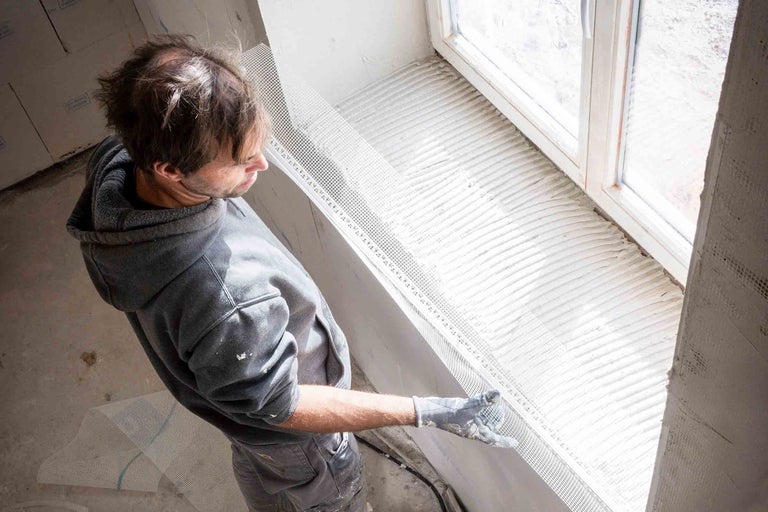 Handwerker befestigt Armierungsgewebe an einem Fenster