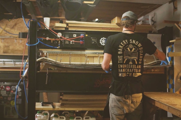 Mann arbeitet an Snowboard-Presse in Werkstatt