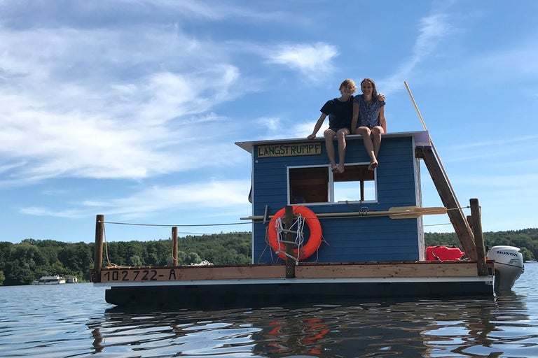 Floss auf dem Wasser mit zwei Personen auf dem Dach, ausgestattet mit Rettungsring und Honda Motor