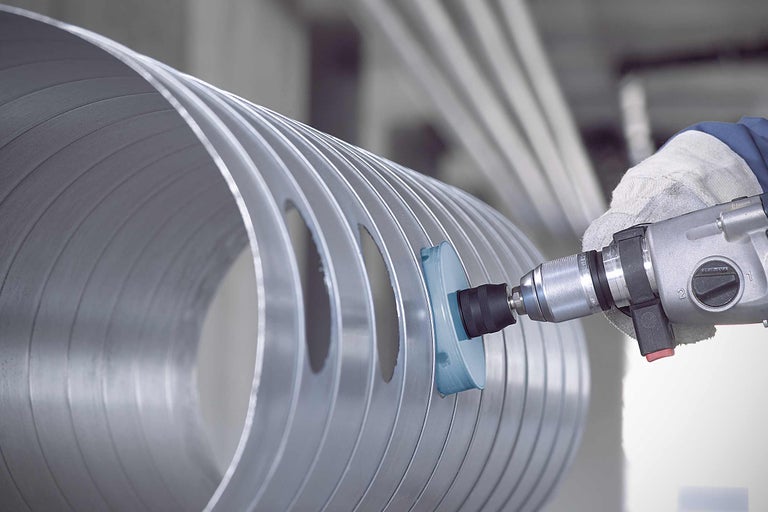 Schleifwerkzeug an einem Aluminiumrohr mit Löchern, das mit einer Bohrmaschine bearbeitet wird