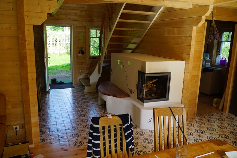 Innenansicht eines Holzhauses mit Treppe, Kamin und Essbereich