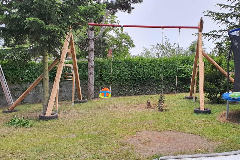 Schaukelgerüst aus Holz und Metall mit mehreren Schaukeln im Garten