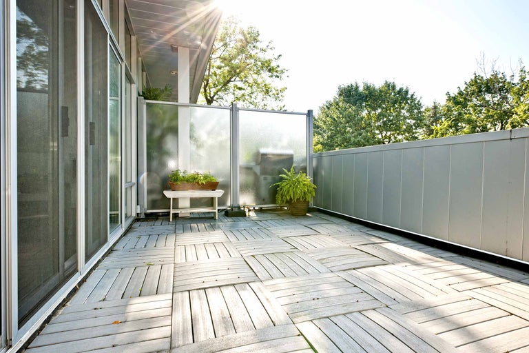 Balkon mit Holzfliesen, Sichtschutzwand und Pflanzgefäßen