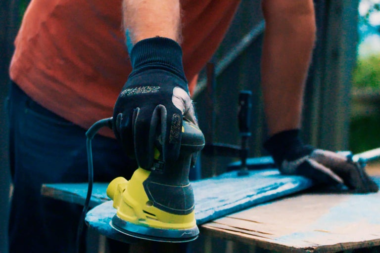 Eine Person schleift Holz mit einem Exzenterschleifer.