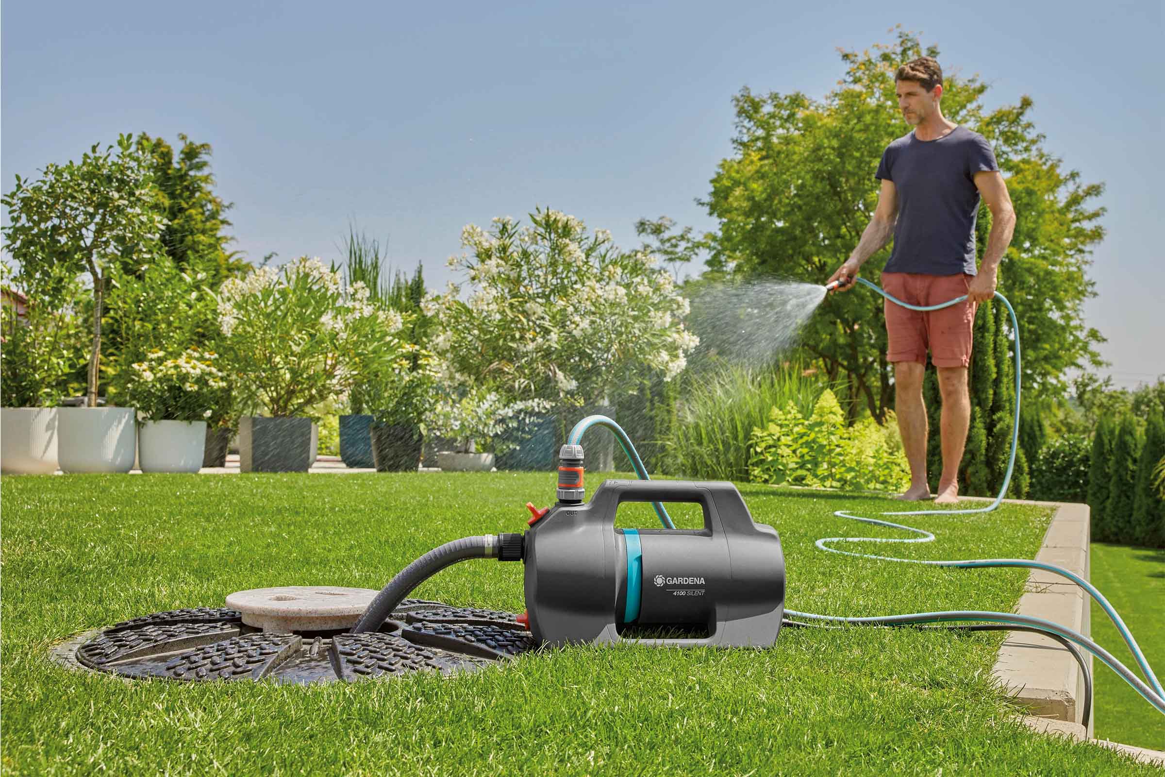 Gartenszene mit Mann, der mit einer Gartenpumpe von Gardena Pflanzen bewässert