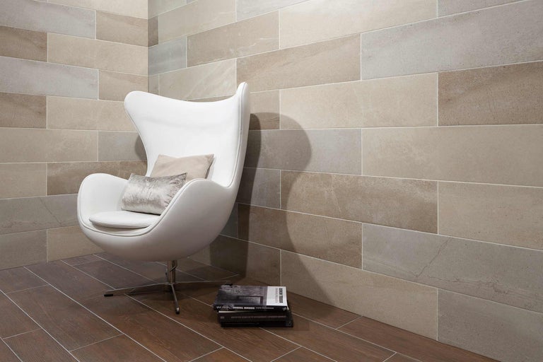 Helles Interieur mit Wand- und Bodenfliesen, Sessel und Büchern