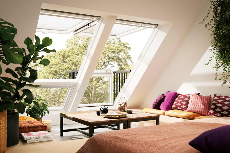 Dachgeschosszimmer mit zwei geöffneten Dachfenstern und Holzbalkon