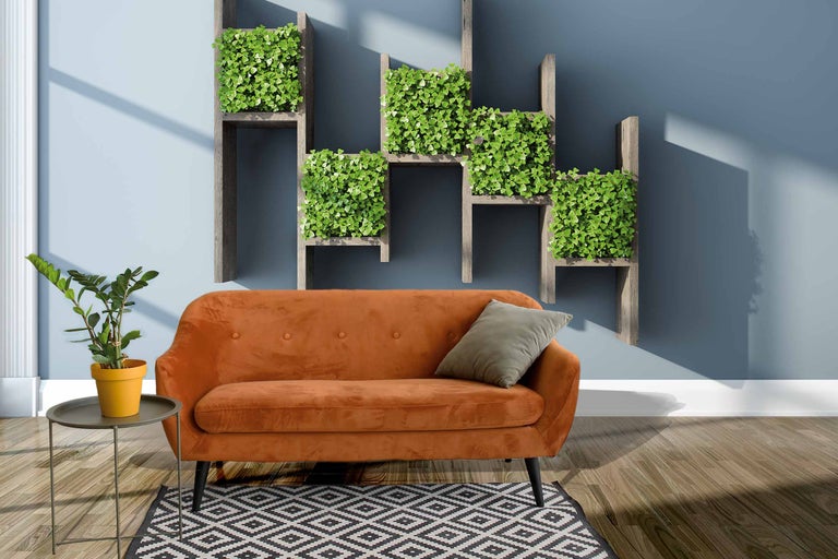 Wohnzimmer mit orangefarbenem Sofa, Pflanzenwand und gemustertem Teppich