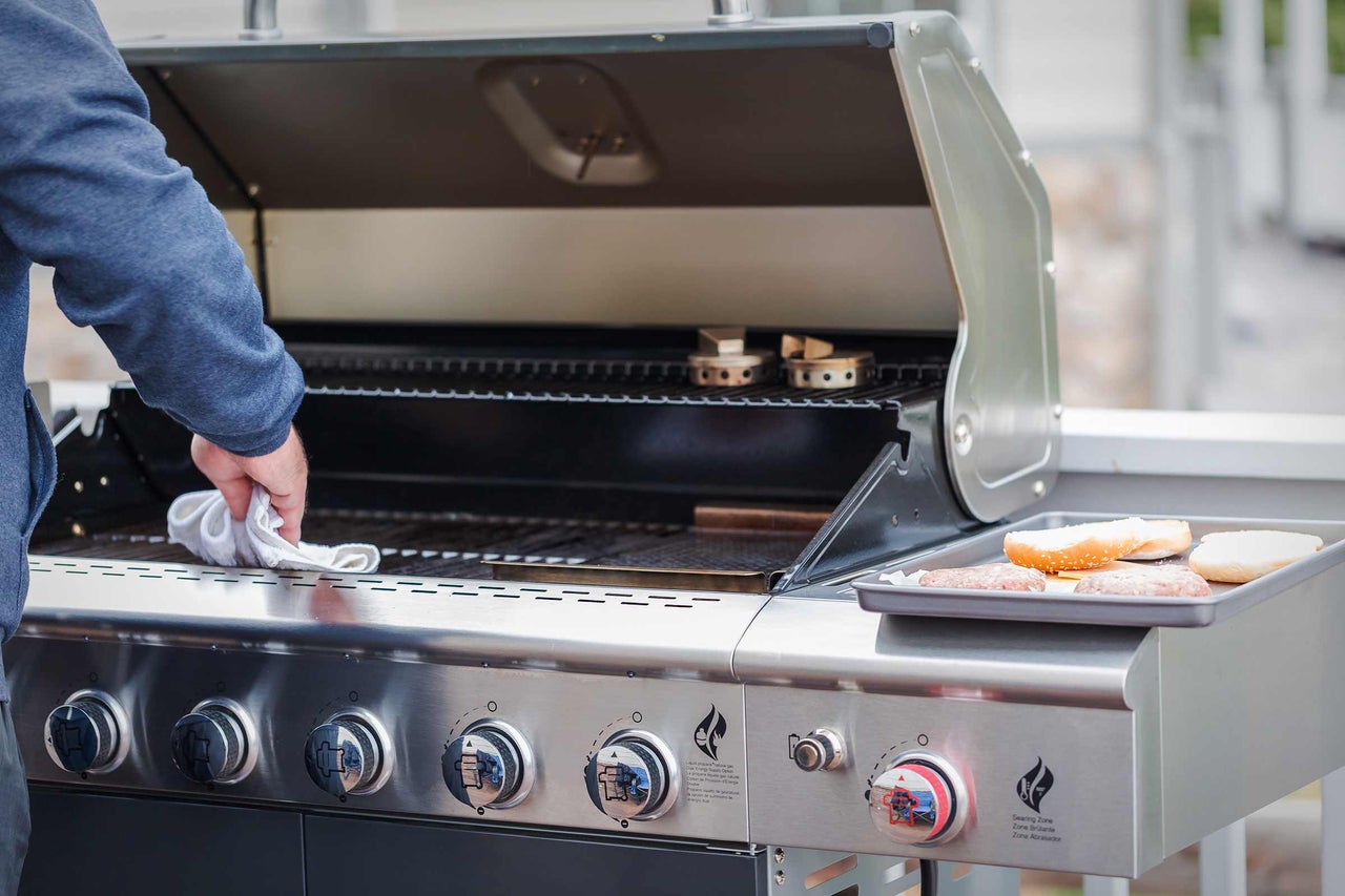 Reinigung eines Gasgrills mit offenem Deckel und Burgern