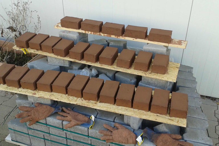 Ziegelsteine auf Paletten mit Arbeitshandschuhen gestapelt