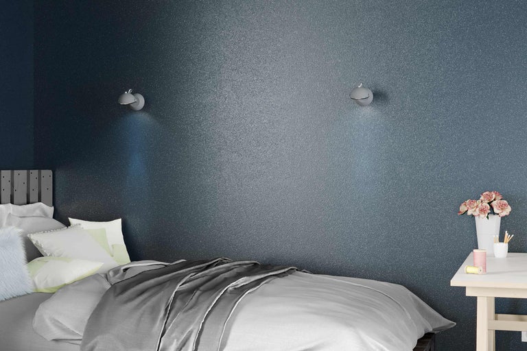 Schlafzimmer mit Bett, Nachttisch und Wandleuchten vor einer strukturierten Wand