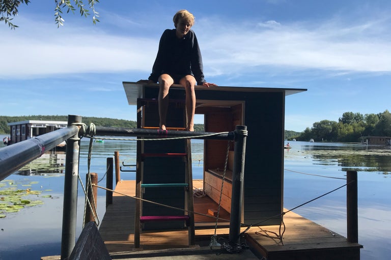 Szene mit einem Badefloß auf einem See, mit Leiter und Person auf dem Dach