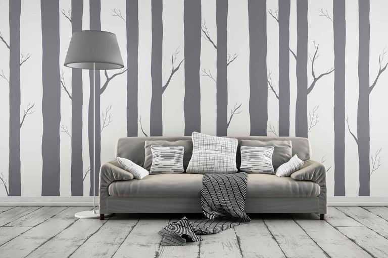 Wohnzimmer mit Sofa, Kissen, Stehlampe und Waldtapete für ein helles und organisiertes Ambiente.