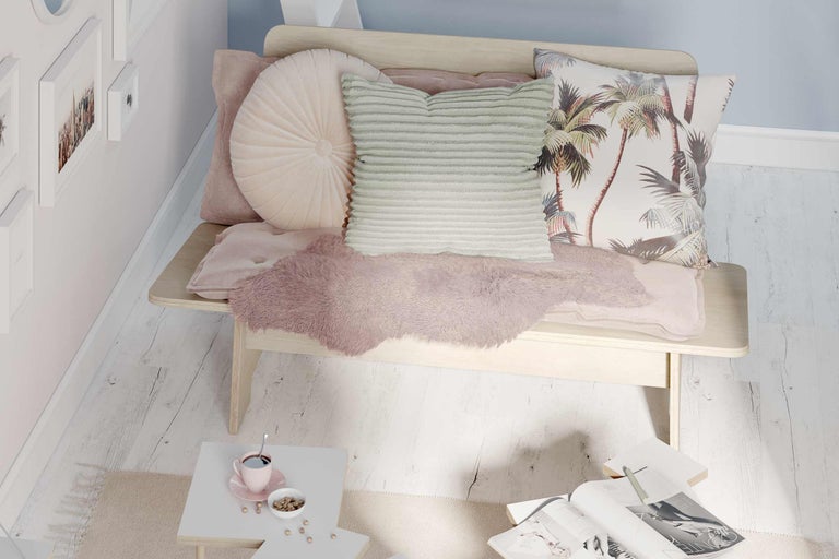 Dekoratives Arrangement mit Kissen und Decken auf einer Bank