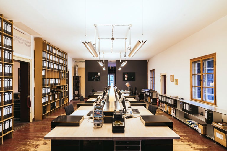 Büroraum mit Schreibtischen, Regalen und Beleuchtung