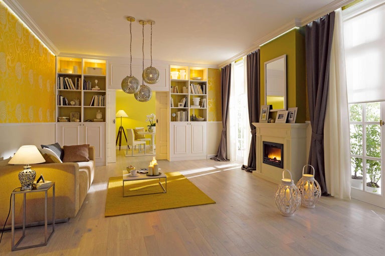 Wohnzimmer mit Couch, Bücherregalen, Kamin und dekorativen Lampen