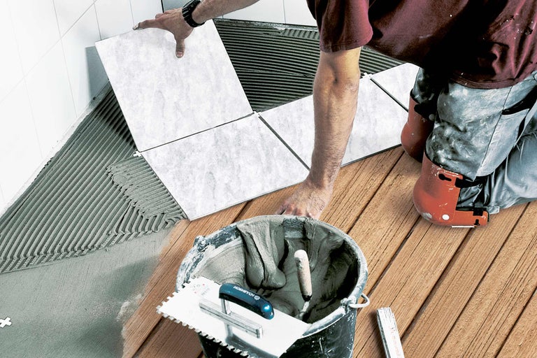Fliesenleger bei der Arbeit im Badezimmer mit Werkzeug