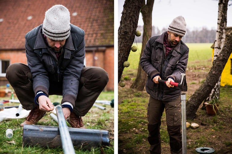 Mann arbeitet im Garten mit einem Hammer und Rohren.