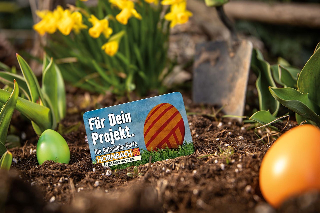 Hornbach Gutscheinkarte im Gartenbeet mit Narzissen und Ostereiern