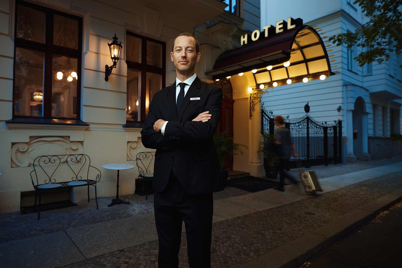 Ein Hoteldiener steht vor einem Hoteleingang.