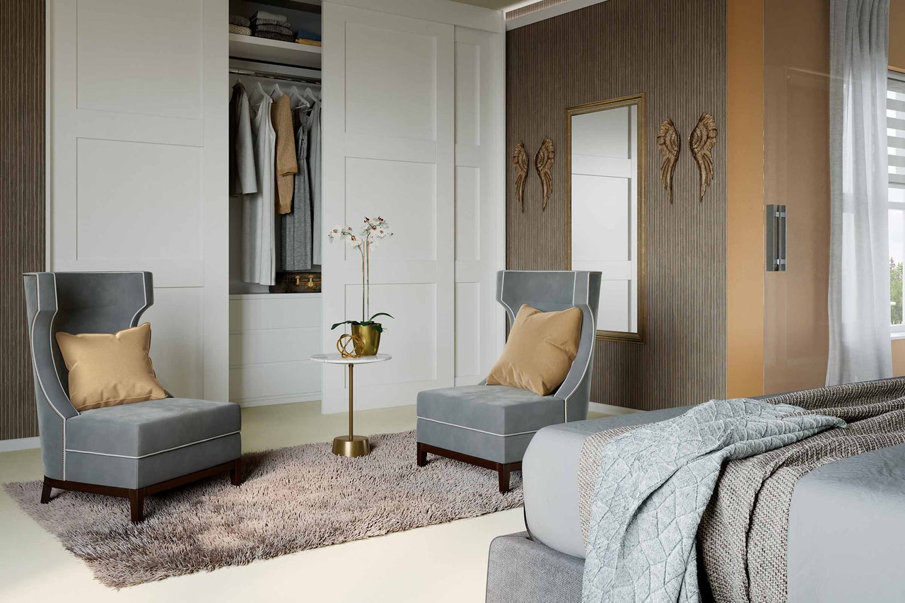 Helles Schlafzimmer mit zwei Sesseln, Bett und Schiebetürenschrank