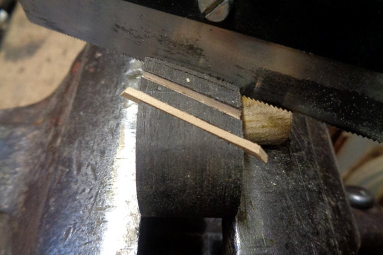 Metallsäge schneidet Holz in Schraubstock