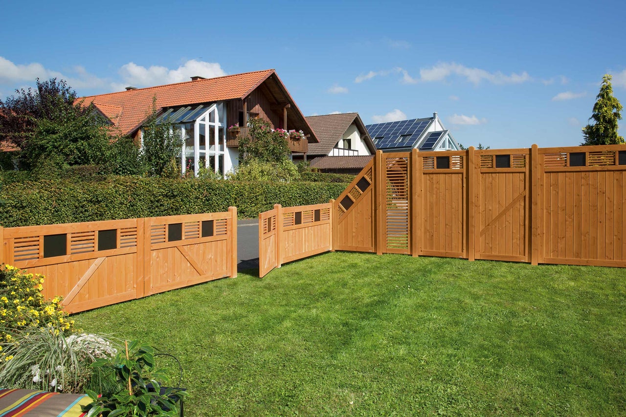 Holzzaun mit Tor im Garten vor Wohnhäusern