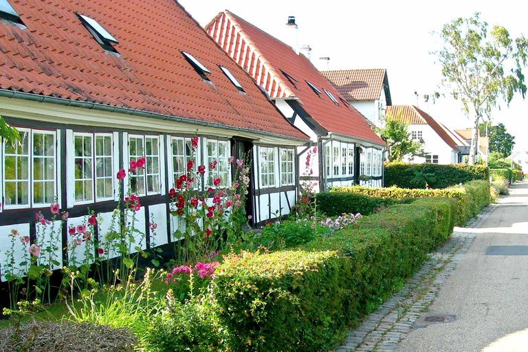 Fachwerkhäuser mit Ziegeldächern und üppigen Gärten entlang einer Straße