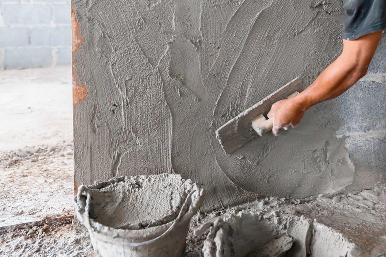 Auftragen von Putz auf eine Wand mit einer Glättkelle
