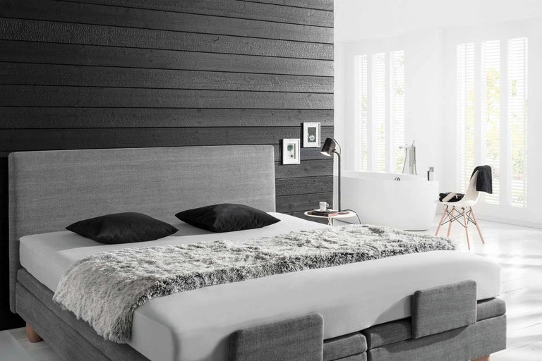 Helles Schlafzimmer mit Boxspringbett, Nachttischlampe und Badewanne
