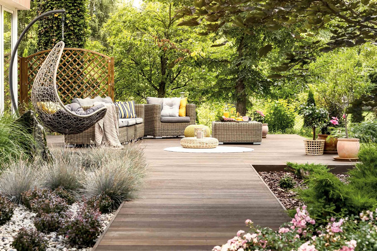 Gartenlounge-Set mit Hängesessel auf einer Holzterrasse im Grünen