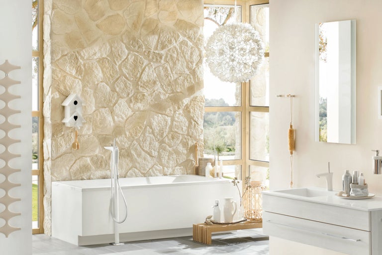 Helles Badezimmer mit Badewanne, Waschtisch und Natursteinwand