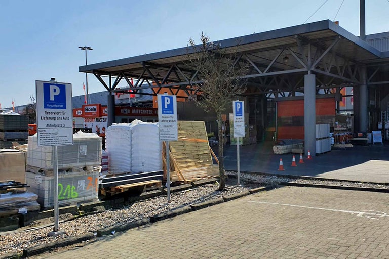 Aussenansicht eines Hornbach Baumarktes mit Parkplatzschildern für die Warenabholung