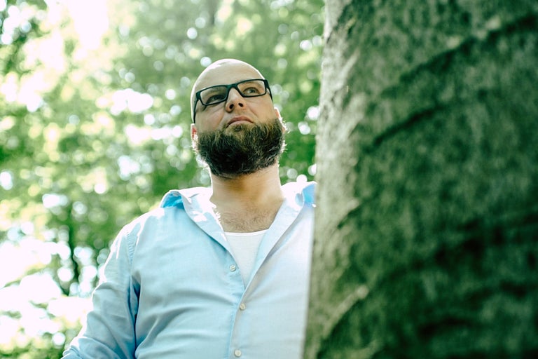 Mann mit Brille steht neben Baum