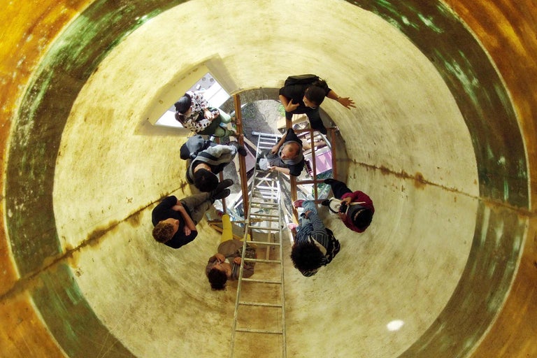 Eine Gruppe von Personen steht auf einer Leiter in einem Tunnel.