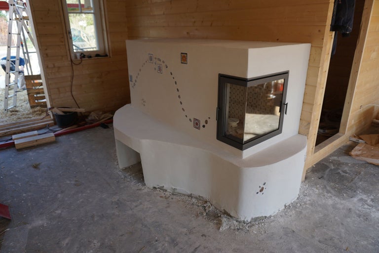 Kachelofen mit Sitzbank und Sichtfenster in einem Holzhaus