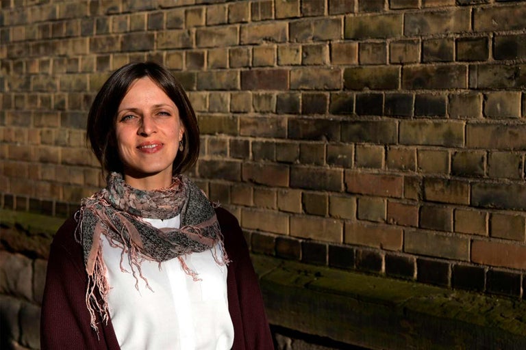 Porträt einer Frau mit Schal vor einer Ziegelwand