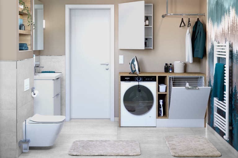 Badezimmer mit Waschbecken, Toilette, Waschmaschine, Trockner, Heizkörper und Aufbewahrungsmöglichkeiten für einen organisierten Raum