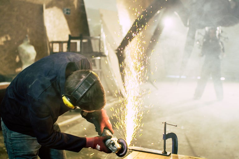 Ein Handwerker bearbeitet Metall mit einem Winkelschleifer, wobei Funken sprühen.