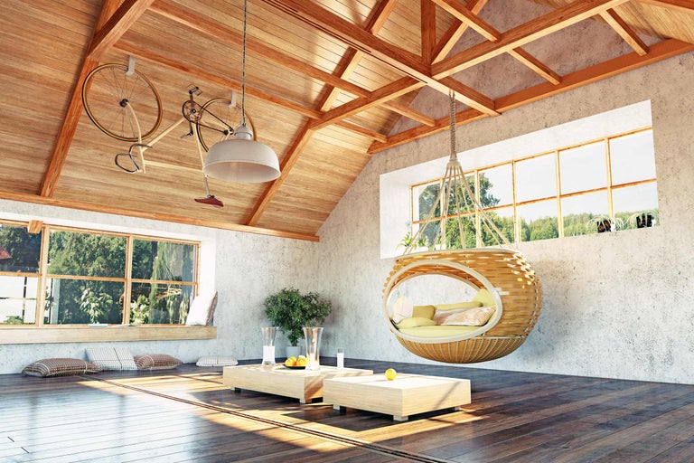 Helles Dachgeschosszimmer mit Holzbalken, Hängekorbsessel und dekorativen Elementen wie Fahrrädern und Kissen