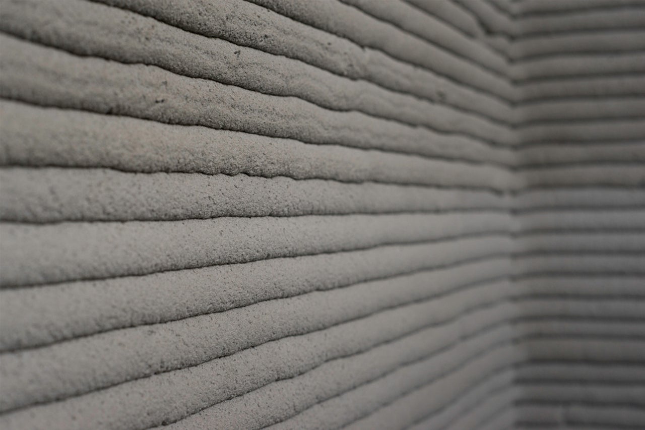 Nahaufnahme einer Wand mit horizontalen Zementlinien, hergestellt im 3D-Druckverfahren.