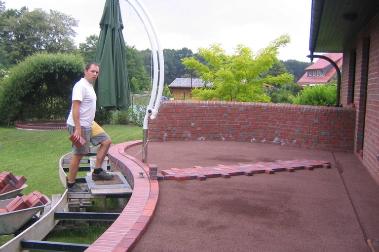 Mann verlegt Pflastersteine im Garten