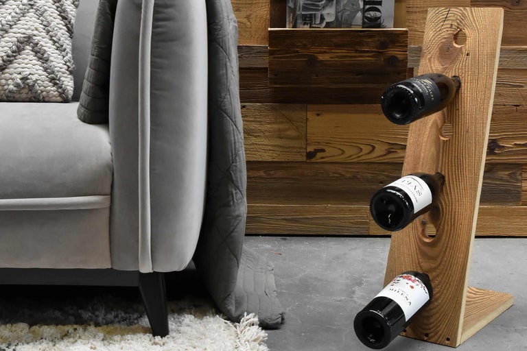 Weinregal aus Holz mit drei Weinflaschen neben einem Sofa.