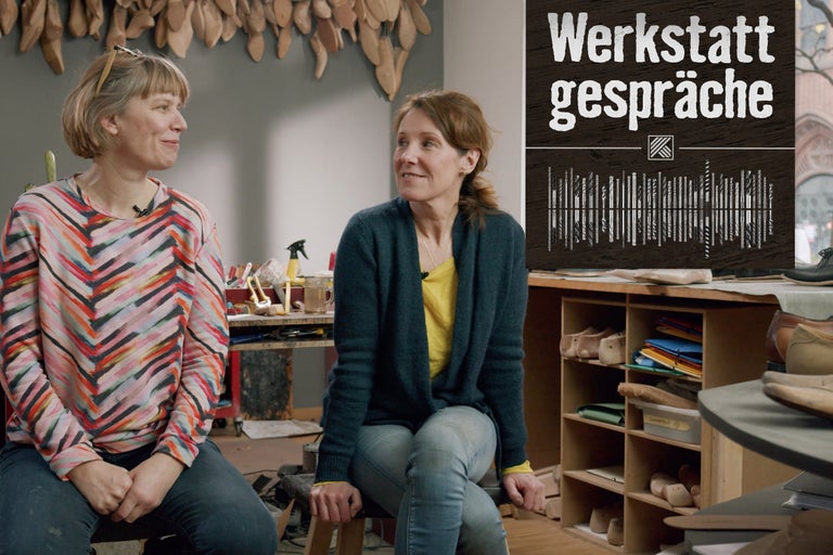 Zwei Frauen sitzen in einer Werkstatt im Gespräch.