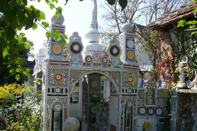 Detailansicht eines kunstvollen Gartengebäudes, verziert mit Keramik und Mosaiken.