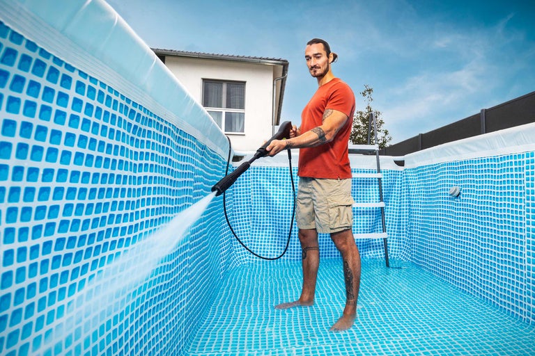 Mann reinigt einen Pool mit einem Hochdruckreiniger.